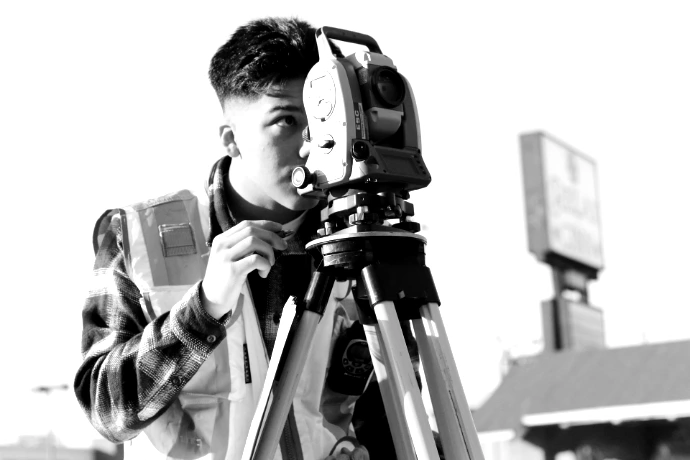 man in gray and orange jacket holding green and black dslr camera during daytime